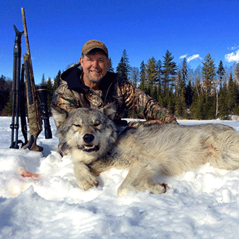 Hunter poses with hunted wolf